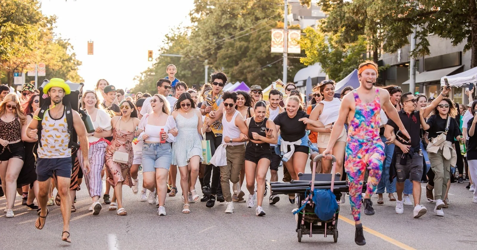 A crowd of attendees running joyfully down a closed street at a joy activation