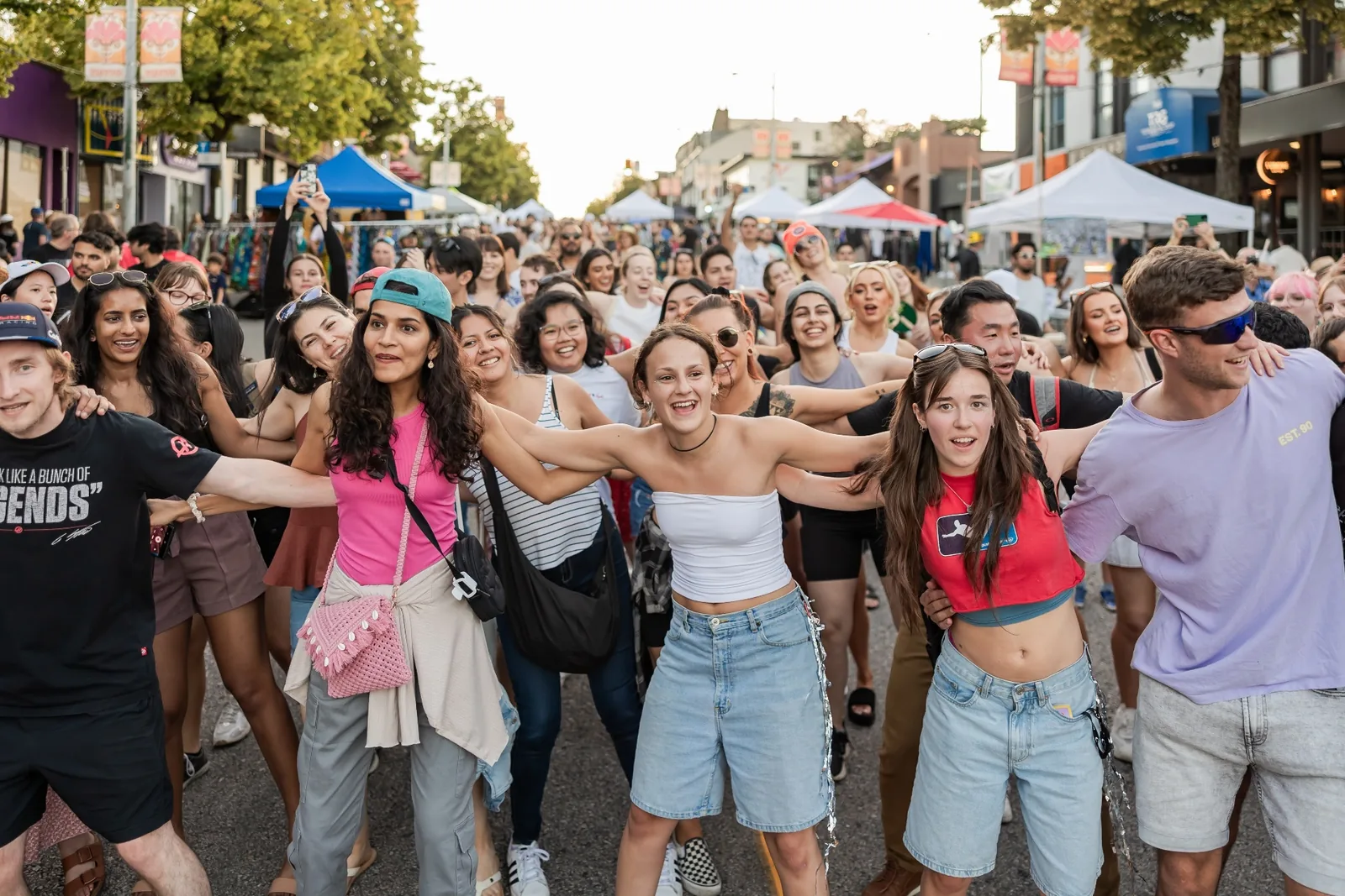 A long human chain of strangers arm-in-arm at a street festival