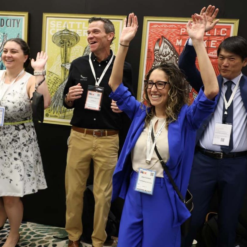 Conference attendees joyfully raising their hands during a joy activation
