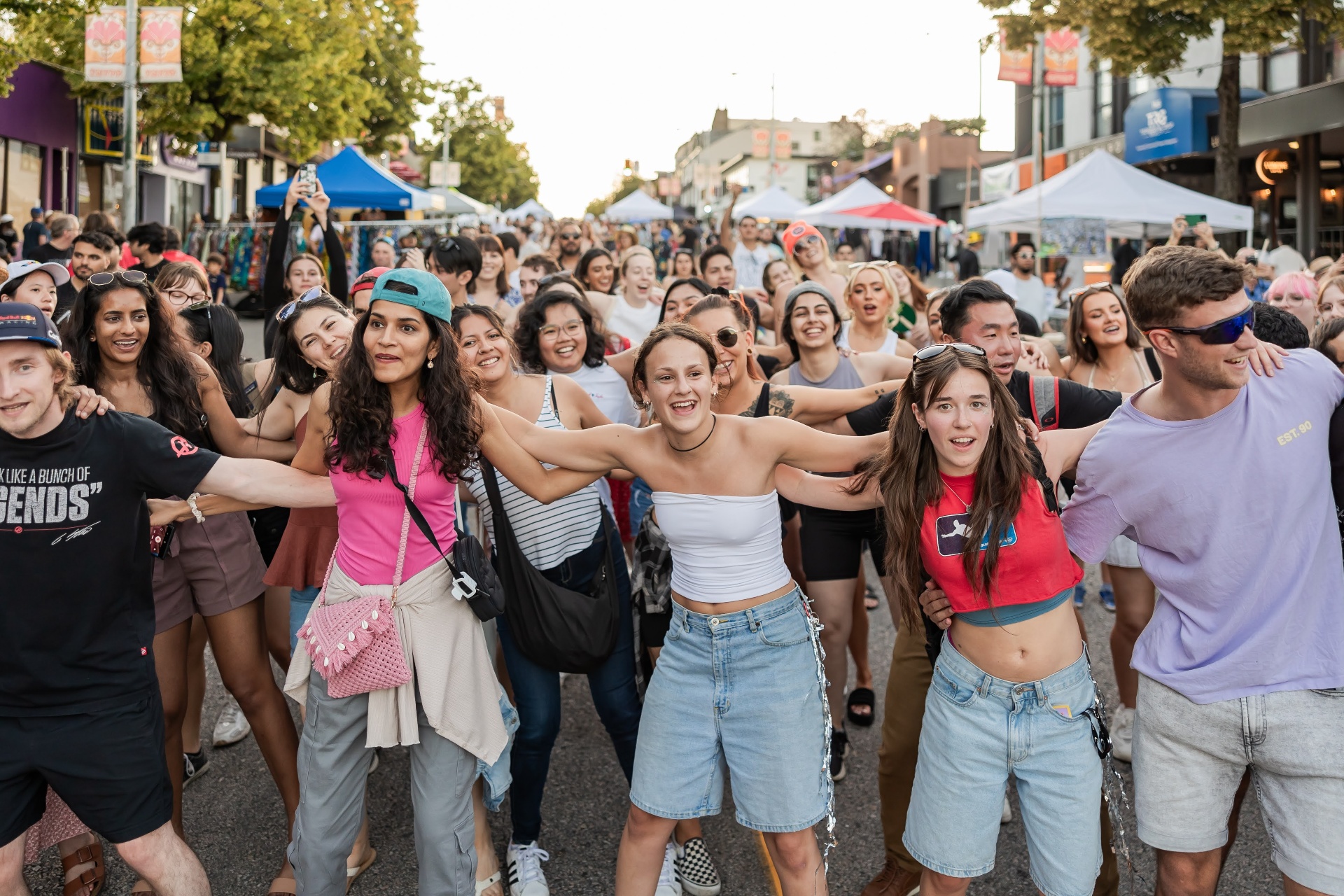 A long human chain of strangers arm-in-arm at a street festival