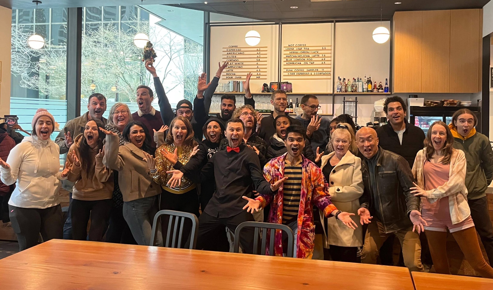 Joymaker crew packed into a Vancouver café, hands in the air, mouths wide open