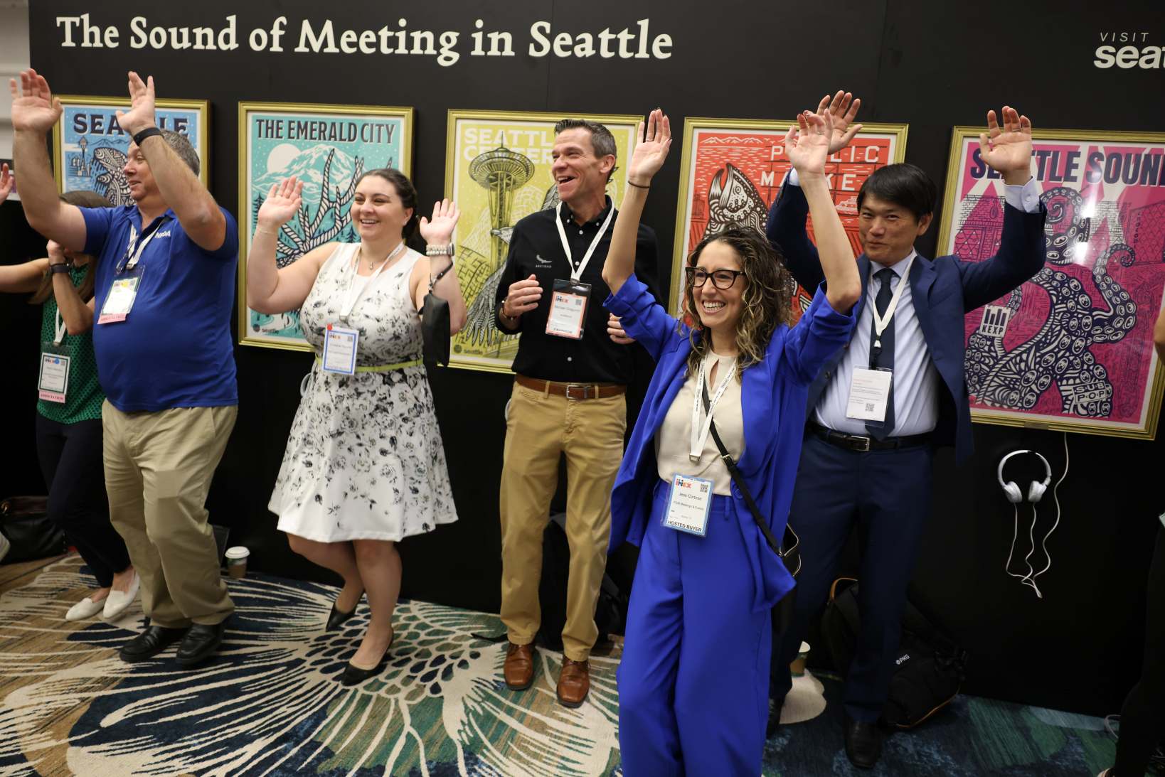Conference attendees with arms raised in a Joymaker session